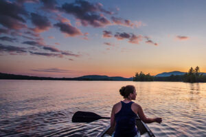 Woman paddling a canoe at sunset