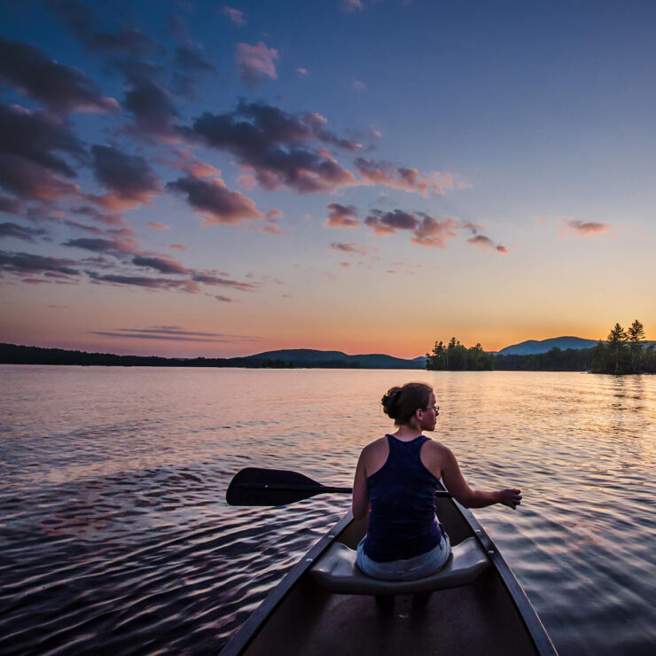 Woman paddling a canoe at sunset