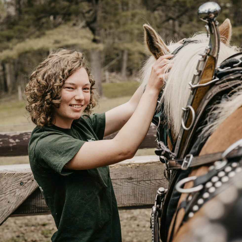 A student poses for a photo while petting a horse