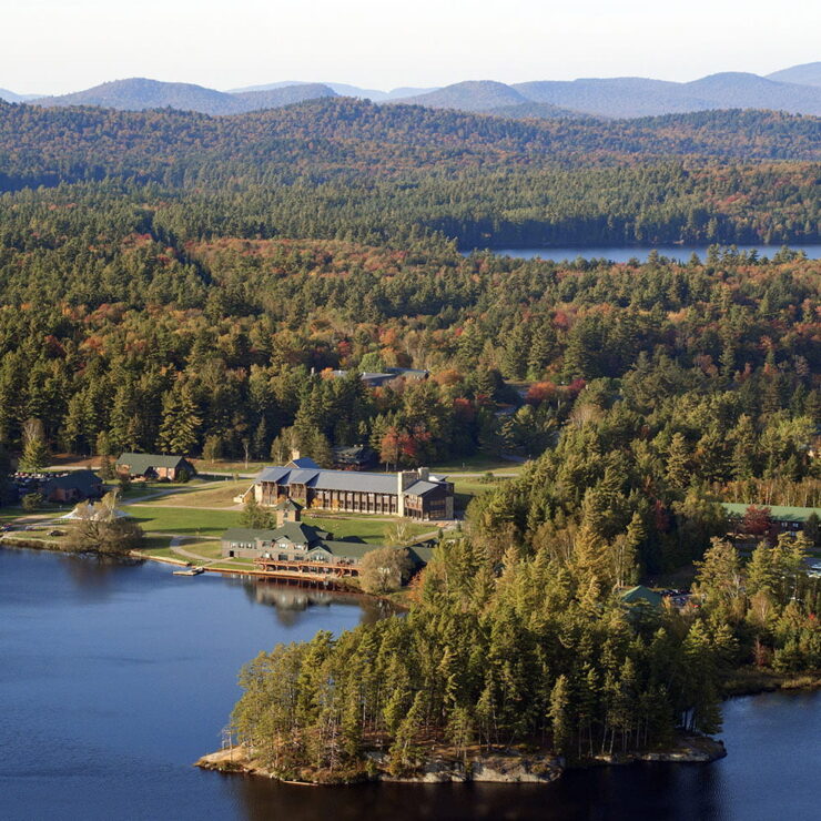 Aerial view of the Paul Smith's College campus with a lake in the foreground and mountains in the distance